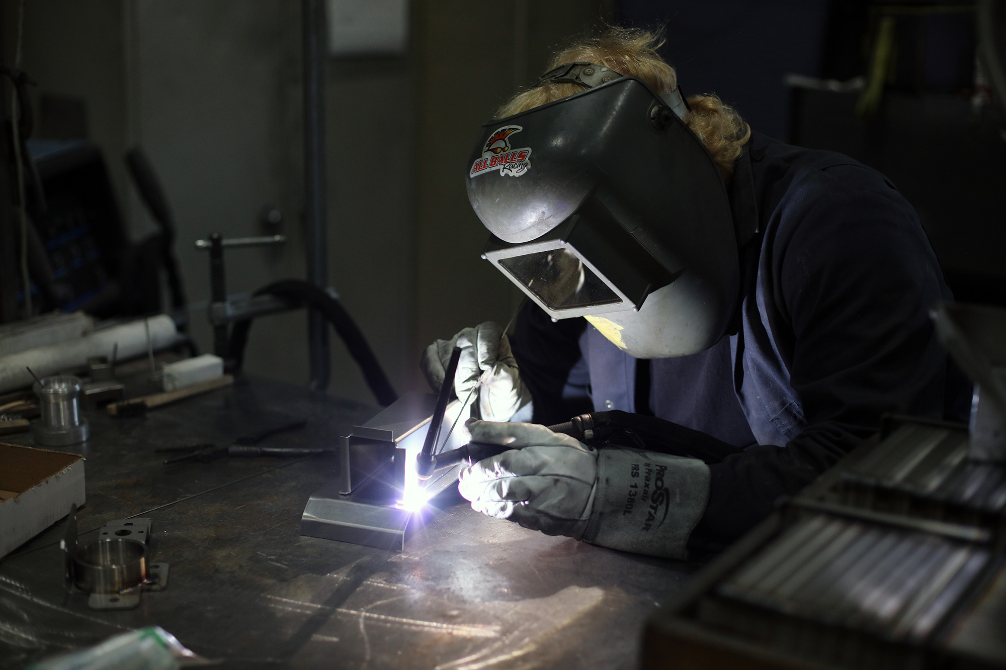 员工焊接戴着焊接口罩和保护性手套的组件